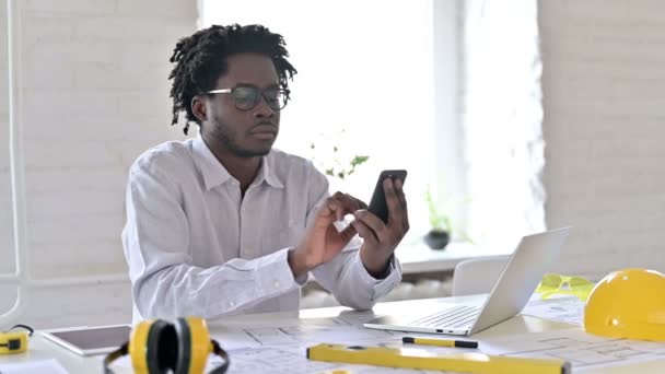 Afrikansk Arkitektur Ingenjör med hjälp av laptop och smartphone i Office — Stockvideo