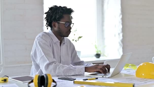 Allvarlig afrikansk arkitekturingenjör som arbetar med bärbar dator på kontoret — Stockvideo
