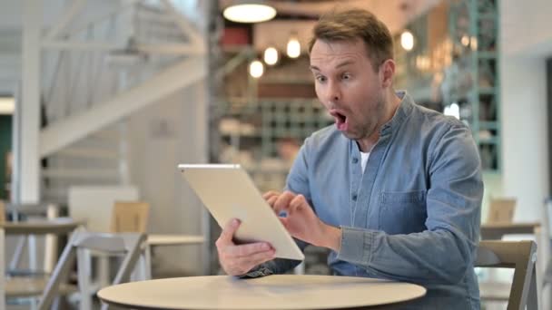 Hombre casual celebrando el éxito en la tableta en el café — Vídeos de Stock