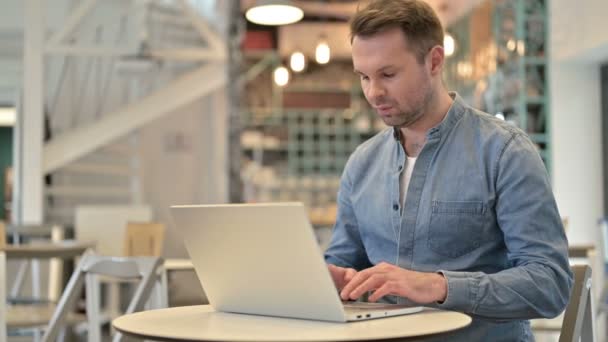 Людина, хвора на спину, користується ноутбуком у кафе — стокове відео