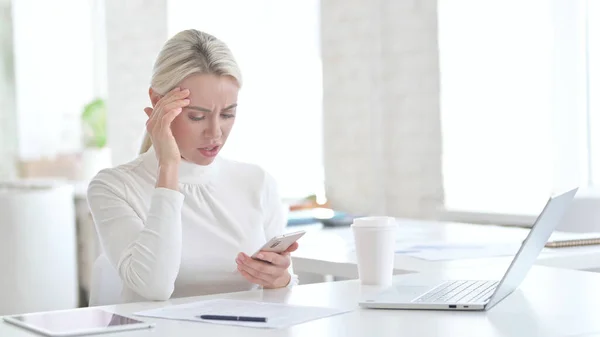 Csalódott fiatal üzletasszony használja okostelefon az irodában — Stock Fotó