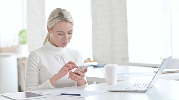 Junge Geschäftsfrau nutzt Smartphone im Büro — Stockfoto