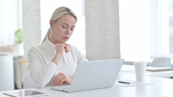 Junge Geschäftsfrau denkt und arbeitet am Laptop — Stockfoto