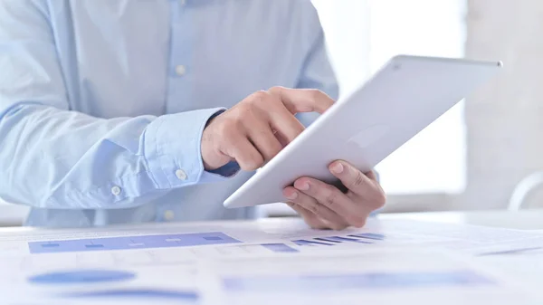 Nahaufnahme eines Mannes, der an Dokumenten und Tablet arbeitet — Stockfoto