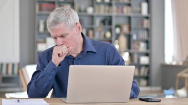 Ofisteki dizüstü bilgisayarda çalışırken hasta adam öksürüyor.