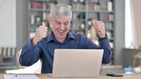 Erfolgreicher Mann feiert mit der Faust, während er im Büro am Laptop arbeitet — Stockfoto