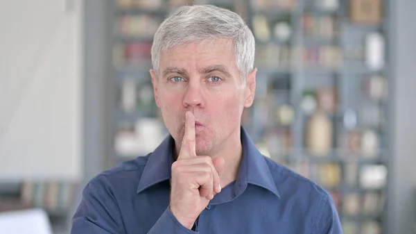 Porträt eines Mannes mittleren Alters, der um Ruhe bittet, indem er den Finger auf die Lippen legt — Stockfoto