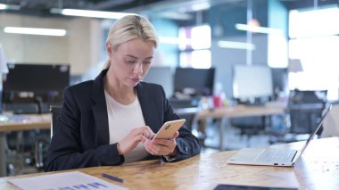 İş yerinde akıllı telefon kullanan ciddi bir iş kadını.