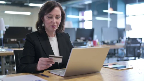 Serious Old Businesswoman Making Online Payment by Credit Card on Laptop