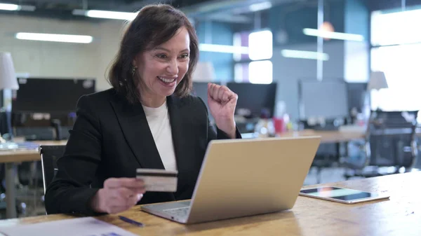 Cheerful Old Businesswoman Celebrating Online Payment Success in Office