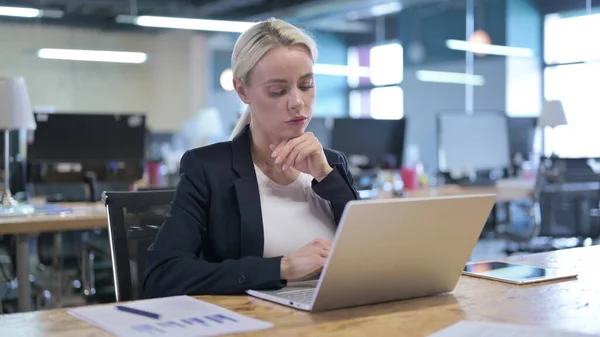 Empresária séria Pensando e trabalhando no laptop no escritório — Fotografia de Stock