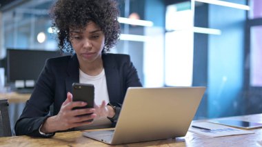 İş yerinde akıllı telefon kullanan ciddi bir iş kadını.