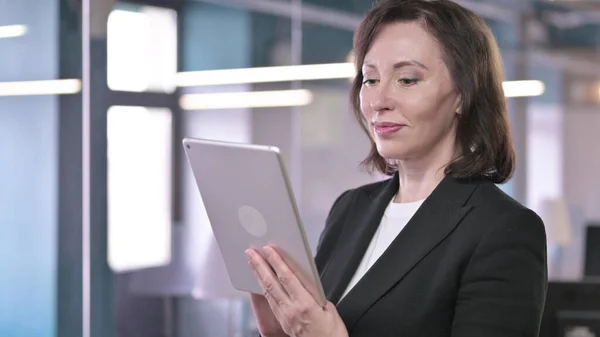 Portrait of Serious Old Businesswoman working on Tablet