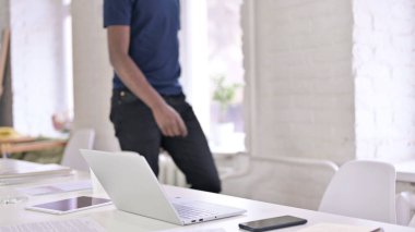 Genç Afrikalı adam geliyor ve ofiste oturuyor.