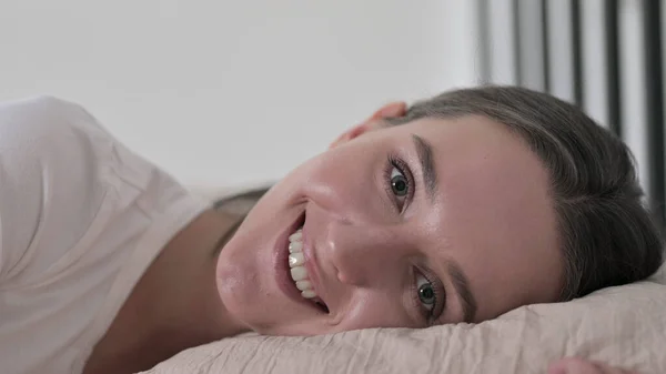 Joyeux jeune femme au lit souriant à la caméra — Photo