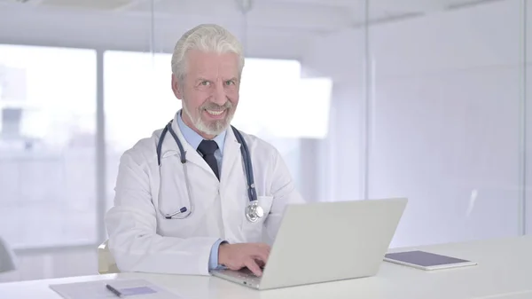 Yaşlı Doktor Klinikteki Kameraya Gülümsüyor — Stok fotoğraf