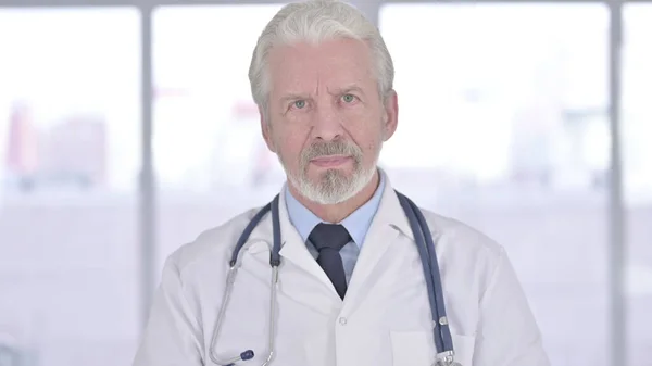 Porträt eines alten Arztes, der in die Kamera blickt — Stockfoto