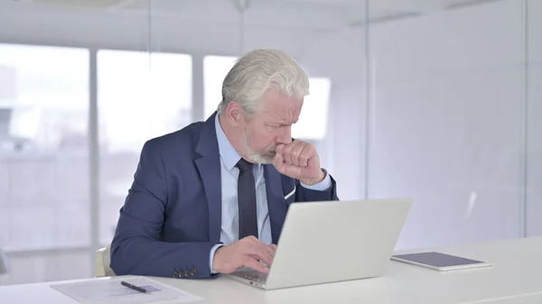 在笔记本电脑和咳嗽上工作的生病的老商人 — 图库照片
