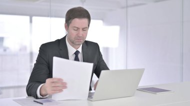 Orta Çağ İşadamı Belgeleri okuyor ve Dizüstü bilgisayarda çalışıyor