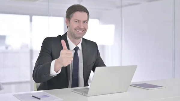 Ambicioso hombre de negocios de mediana edad haciendo pulgares hacia arriba en la oficina —  Fotos de Stock