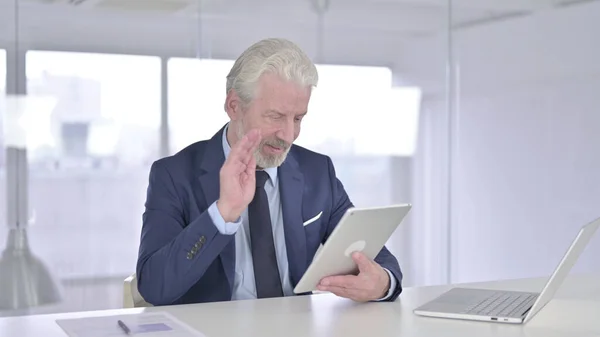 Vieux homme d'affaires qui fait du chat vidéo sur tablette dans le bureau — Photo