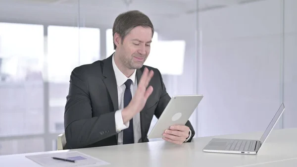 Uomo d'affari di mezza età che fa videochat su tablet in ufficio — Foto Stock