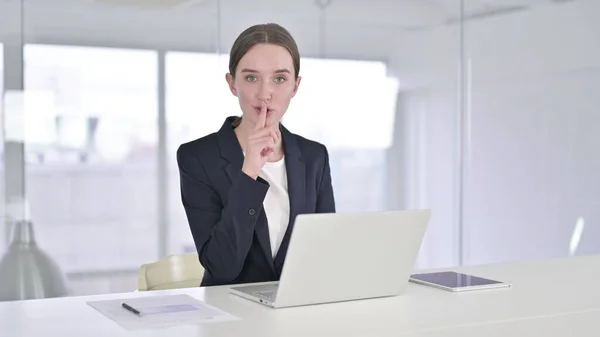Umtriebige junge Geschäftsfrau legt im Büro Finger auf Lippen — Stockfoto