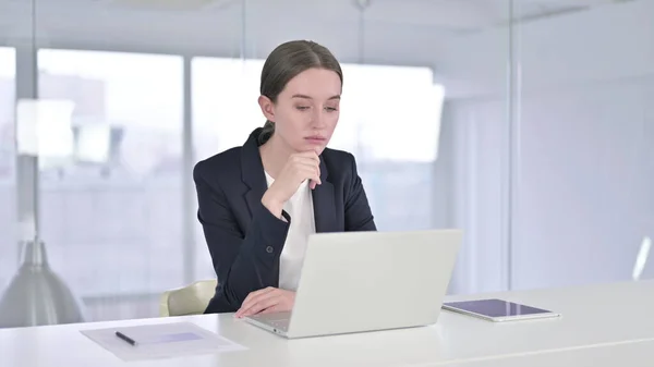 Jonge zakenvrouw denken en werken op Laptop in Office — Stockfoto