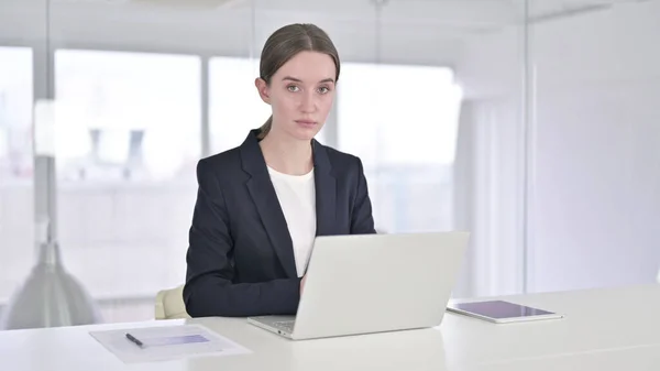 Sérieux jeune femme d'affaires regardant la caméra au travail — Photo