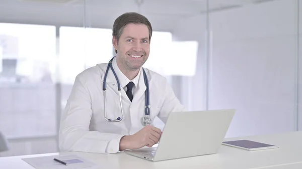 Доктор средних лет улыбается на камеру в клинике — стоковое фото
