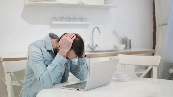 Triste barba jovem enfrentando perda no laptop — Fotografia de Stock