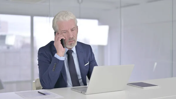 Vecchio uomo d'affari serio che parla su Smartphone in ufficio — Foto Stock