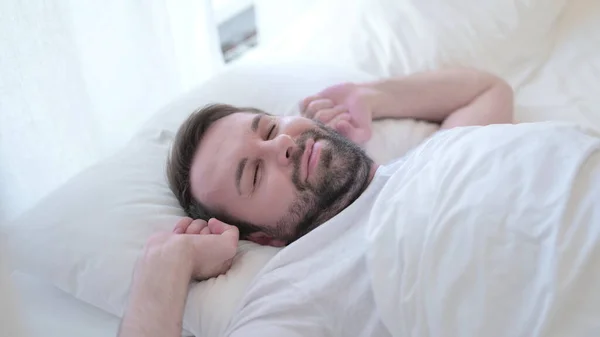 Atraktivní vousy Mladý muž probouzí a vstává z postele — Stock fotografie