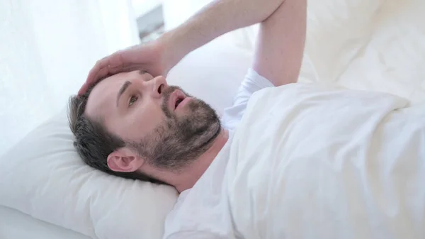 Porträtt av skäggig ung man med mardröm i sängen — Stockfoto