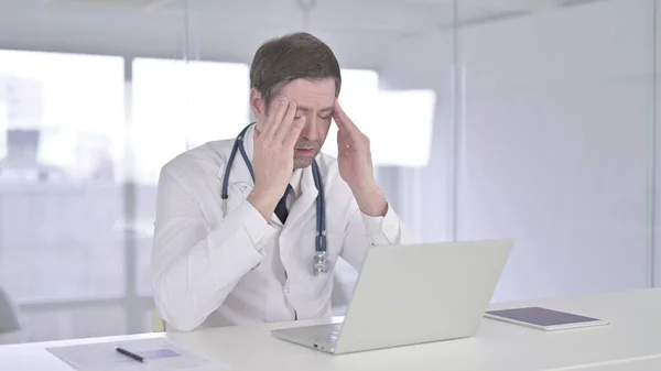 Уставший врач среднего возраста с головной болью — стоковое фото