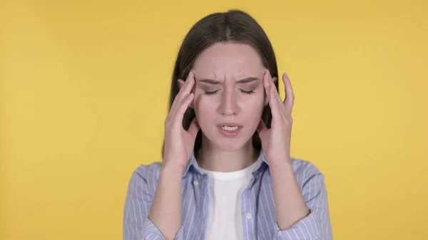 Giovane donna con mal di testa su sfondo giallo — Foto Stock