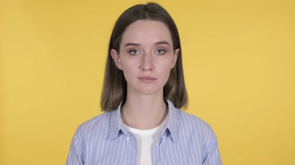 Jovem mulher olhando para a câmera no fundo amarelo — Fotografia de Stock