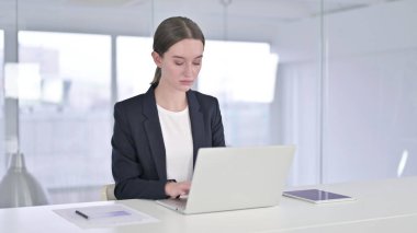 Ofiste dizüstü bilgisayarda çalışan hırslı genç iş kadını.