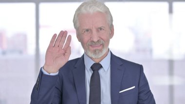 Kameraya el sallayan yaşlı iş adamının portresi.