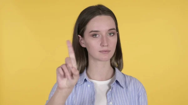 Młoda kobieta macha palcem, aby odmówić na żółtym tle — Zdjęcie stockowe