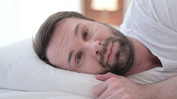 Zbliżenie w górę z poważnie broda młody człowiek patrząc w kamery w łóżko — Zdjęcie stockowe