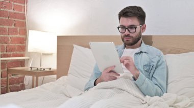 Yatakta Tablet kullanan Odaklanmış Genç Adam