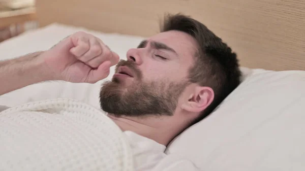 Hasta genç adam yatakta öksürüyor. — Stok fotoğraf