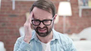 Çatı katında başı ağrıyan yorgun sakallı genç adamın portresi 