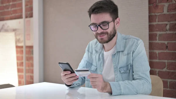 Hombre joven en gafas haciendo pago en línea en Smartphone — Foto de Stock