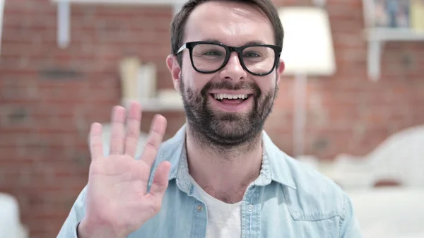 Porträt eines fröhlichen jungen Mannes mit Bart, der in die Kamera winkt — Stockfoto