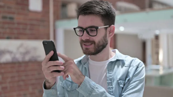 스마트 폰 을 사용하여 안경을 쓴 즐거이 하는 청년 — 스톡 사진