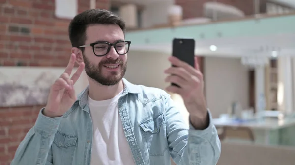 Молодой человек в очках делает селфи на смартфоне — стоковое фото
