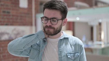 Gözlüklü yorgun genç adam boyun ağrısı çekiyor.