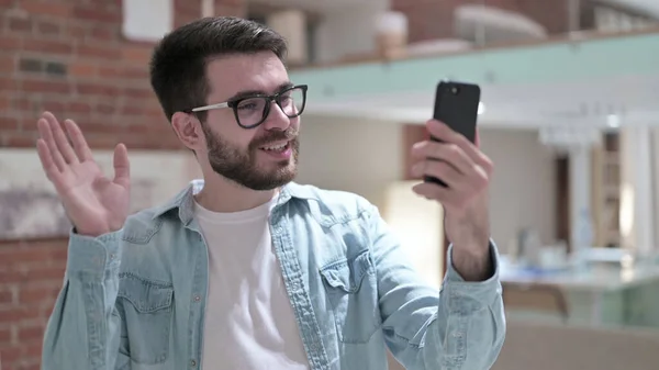 戴眼镜的年轻人在智能手机上做视频聊天 — 图库照片